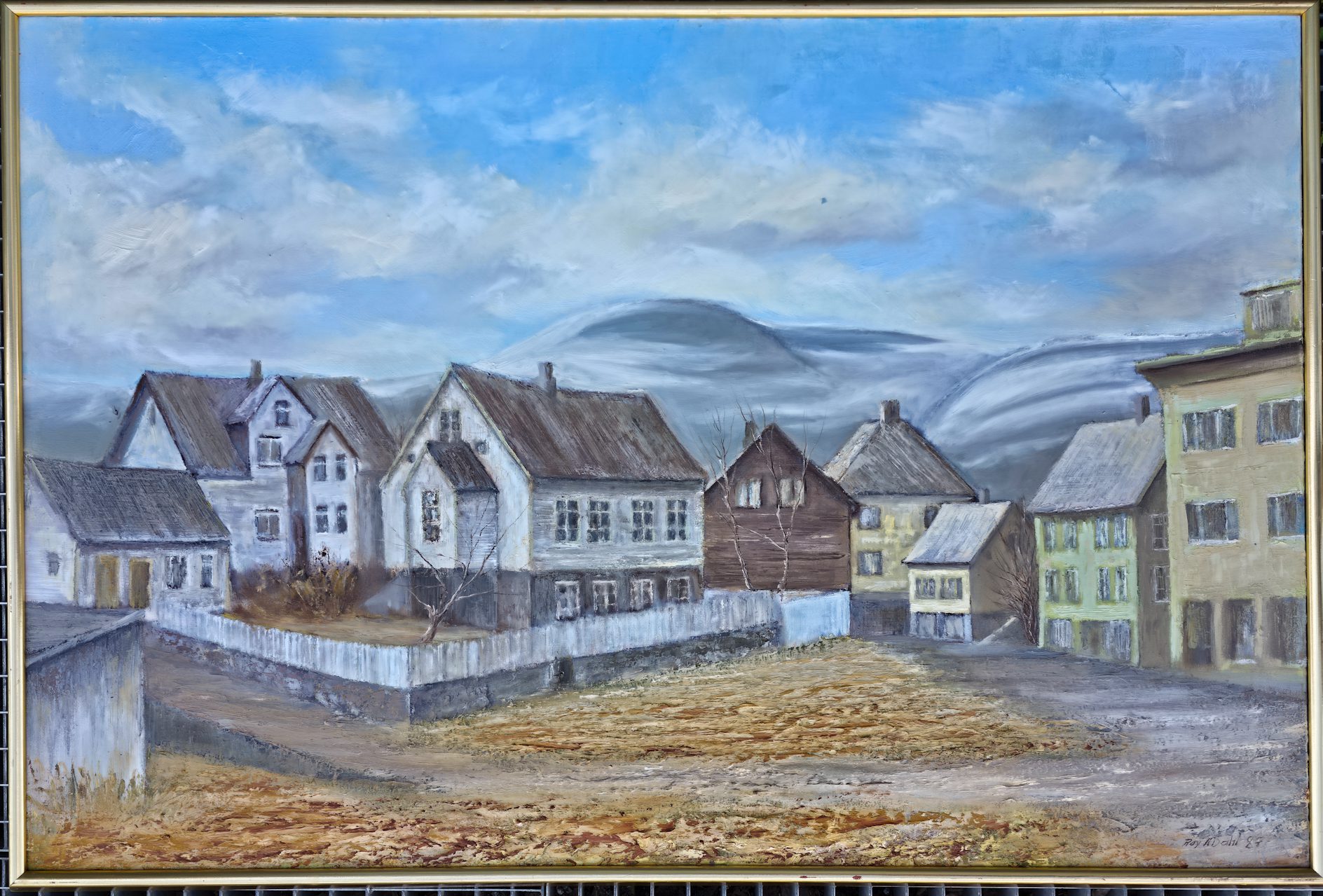 Signert oljemaleri på lerret av Roy Andreas Dahl fra 1987. Stemningsfullt bylandskap med eldre trehusbebyggelse og fjell i bakgrunnen.